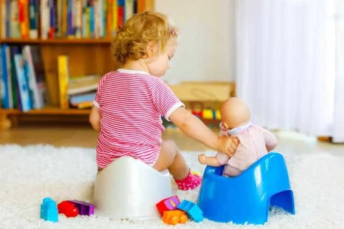 toddler playing with baby on potty chair