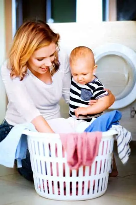 mom holding baby while she does laundry