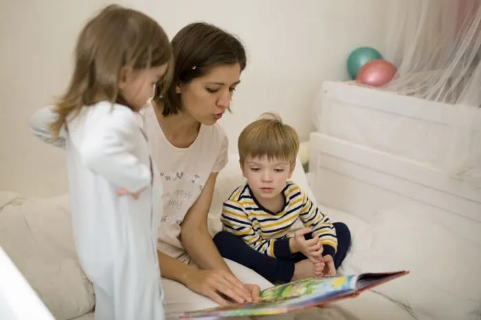 mom reading book to two kid with pajamas on for bedtime routine