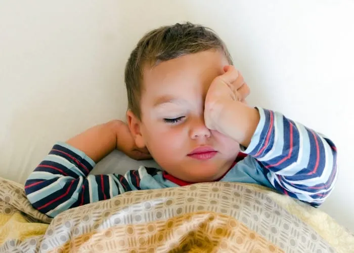 toddler rubbing eyes in bed
