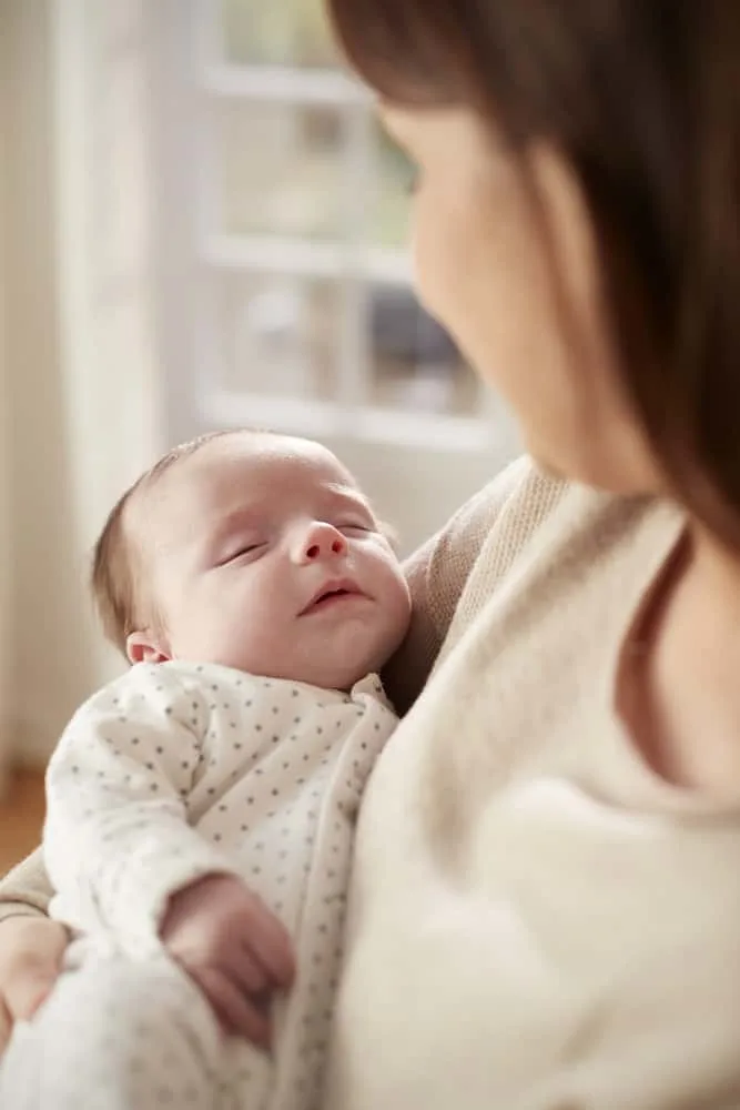 newborn baby sleeping in moms arms