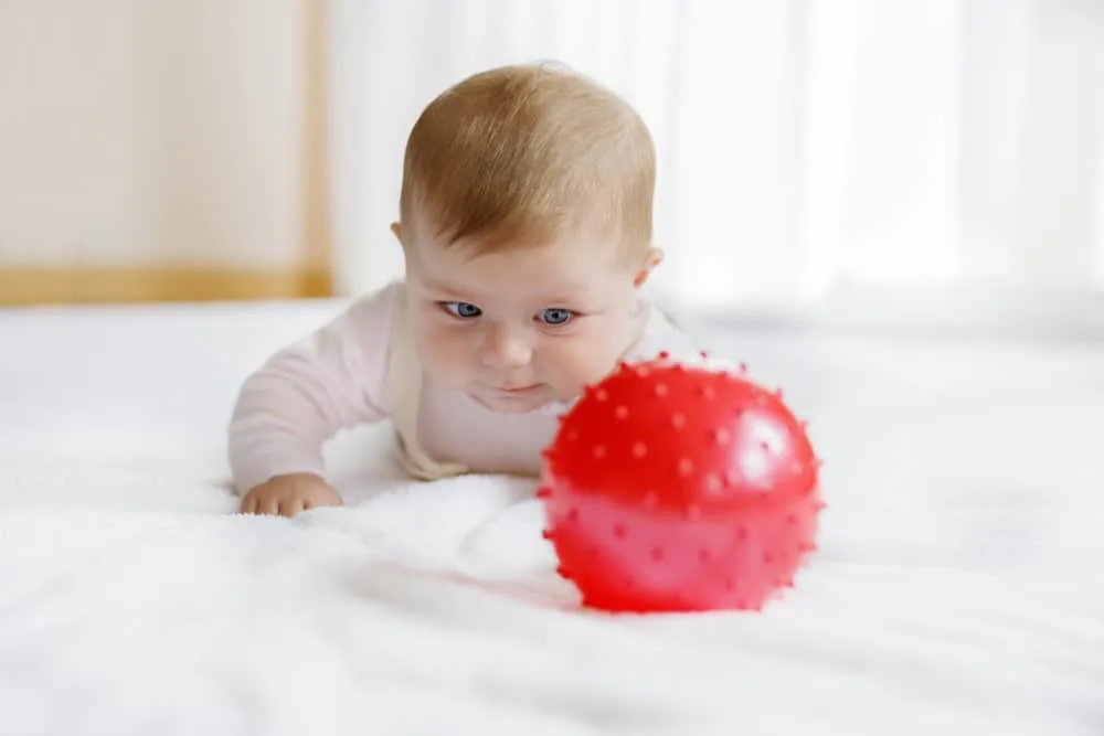 baby doing tummy time playing with a ball
