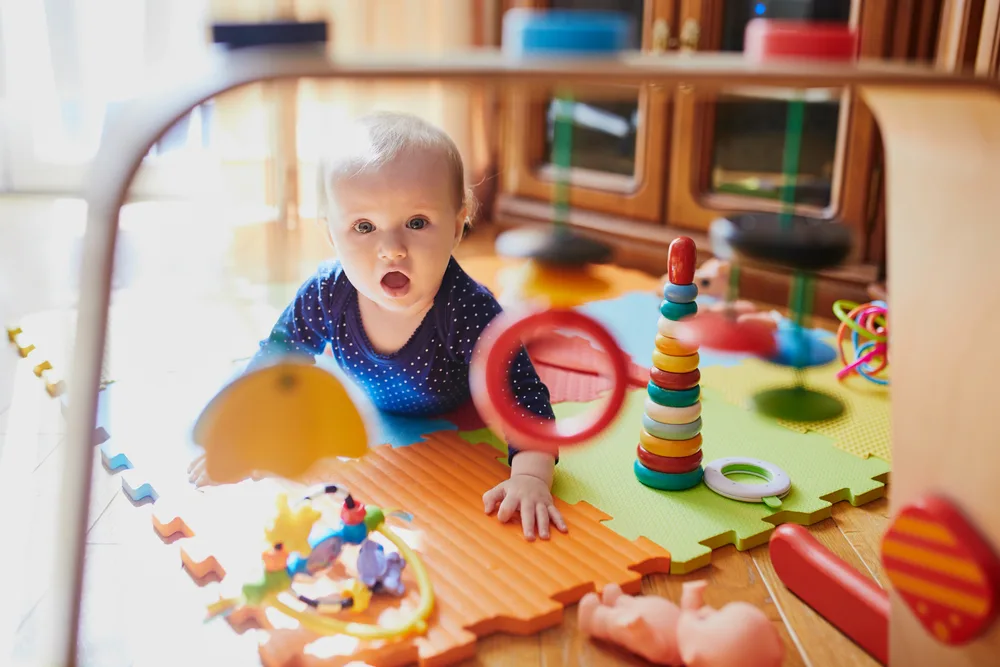 Baby girl playing with toys on the floor. Happy healthy little child at home