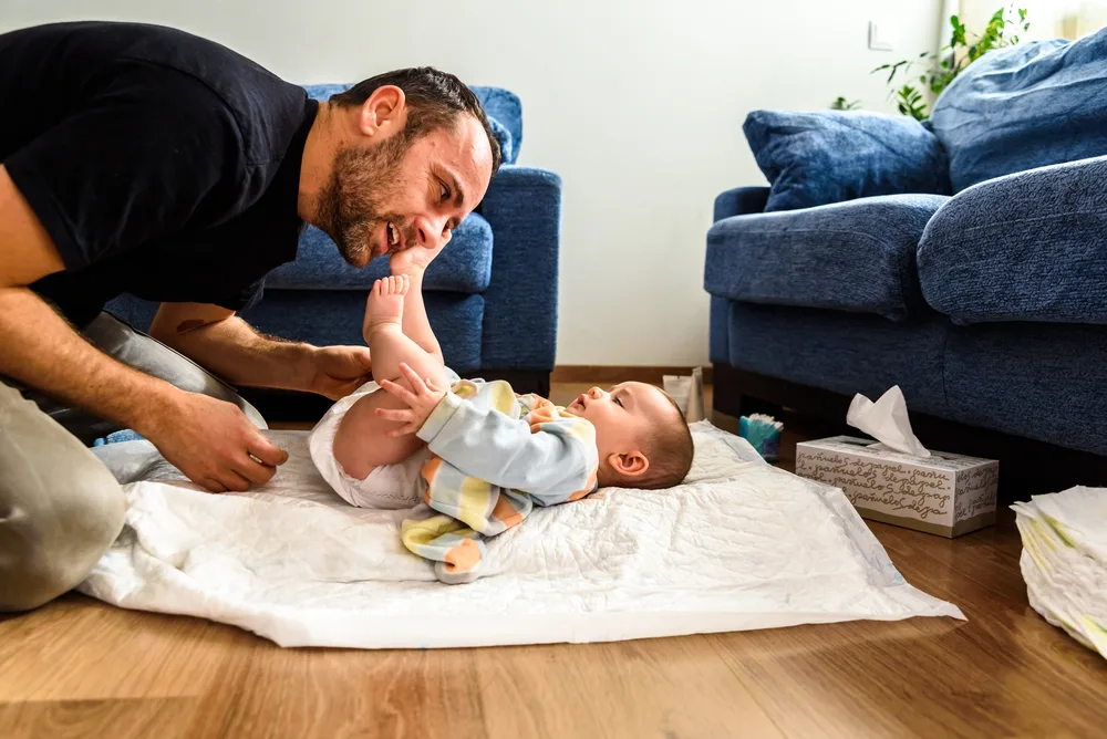 Father changing his daughter's dirty diaper.