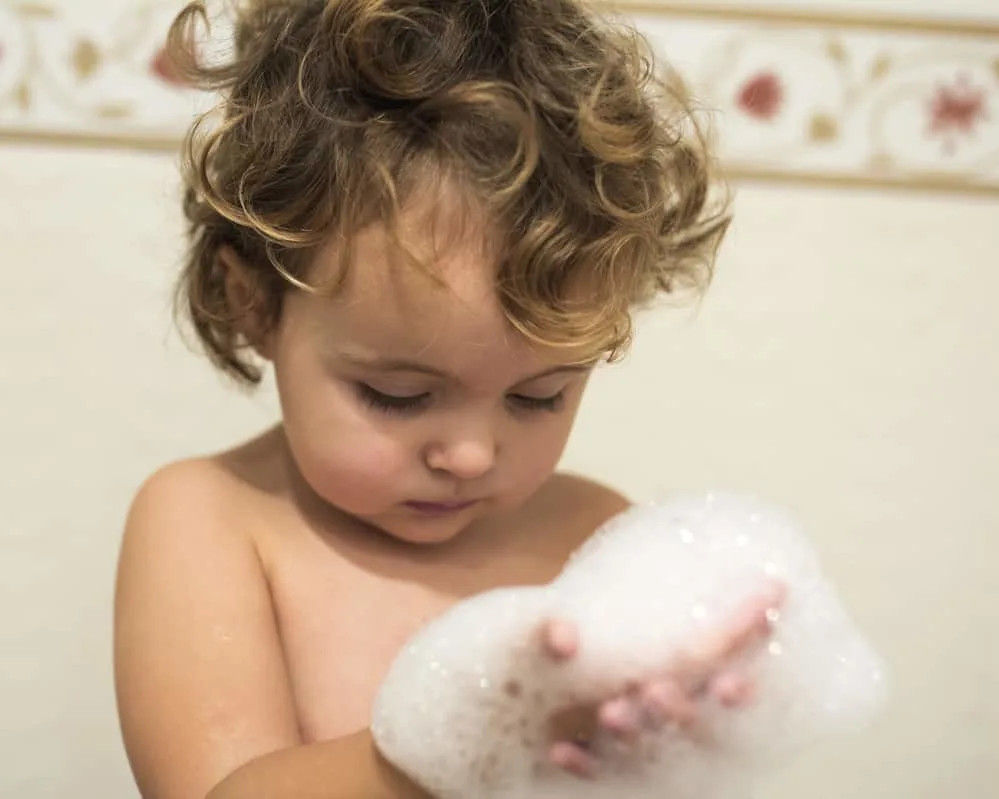 little girl holding bubbles in the bath