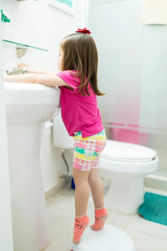 Full length of little toddler washing hands in sink at home